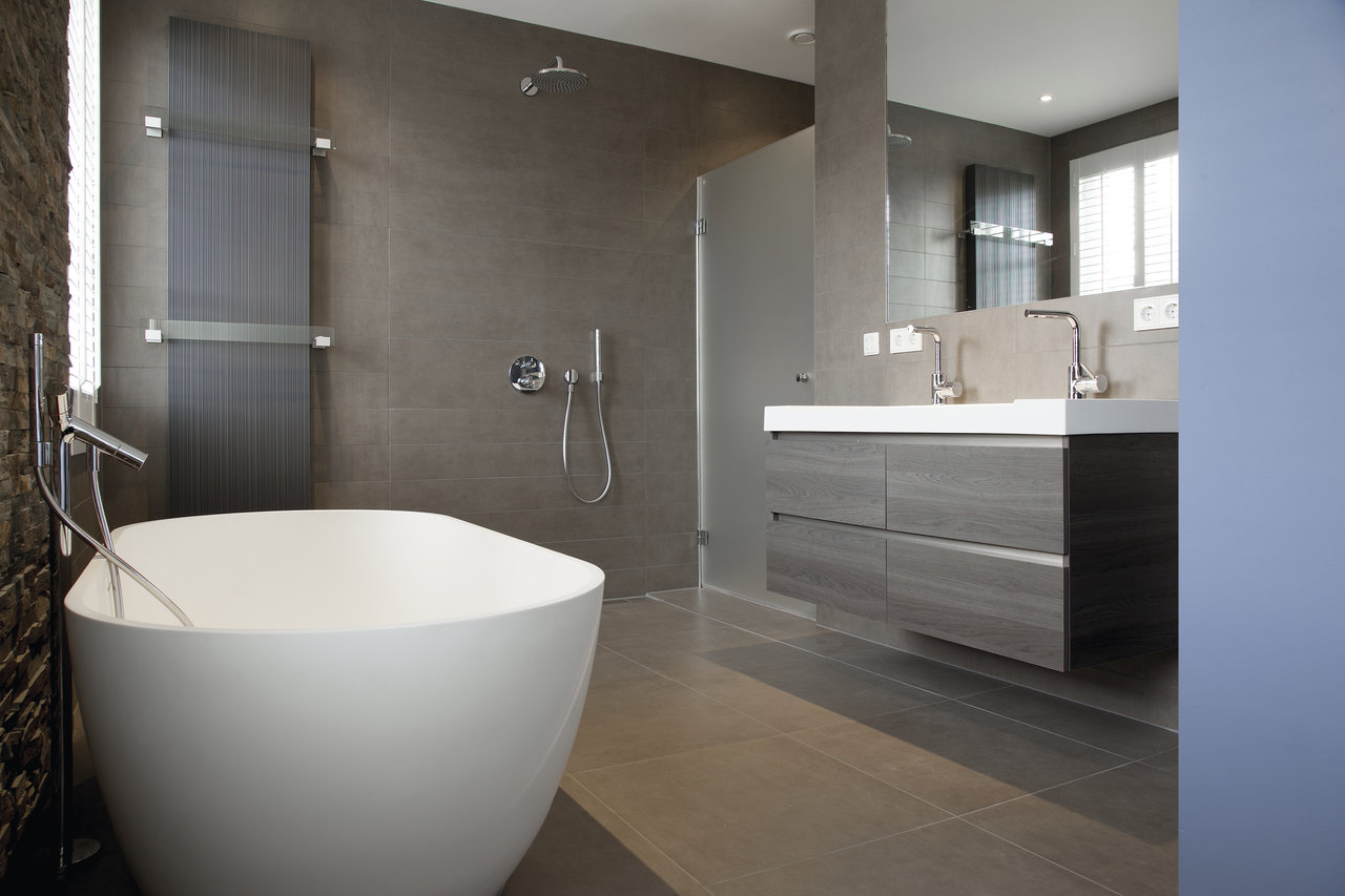 Modernes Badezimmer mit hochwertigen, großformatigen Fliesen in Grau an Wänden und Boden.