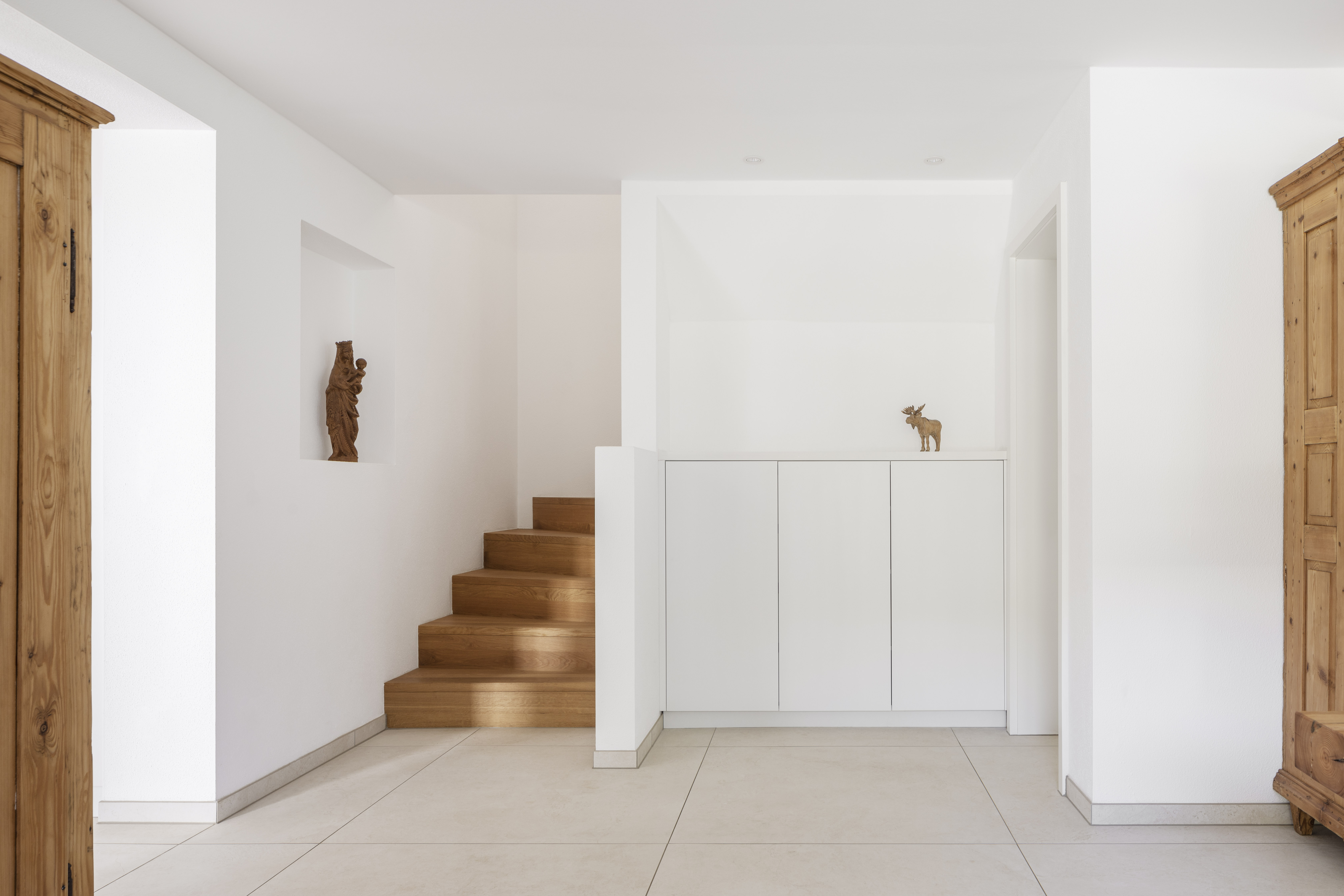 Helle, moderne Bodenfliesen in einem stilvollen Eingangsbereich mit Holztreppe.