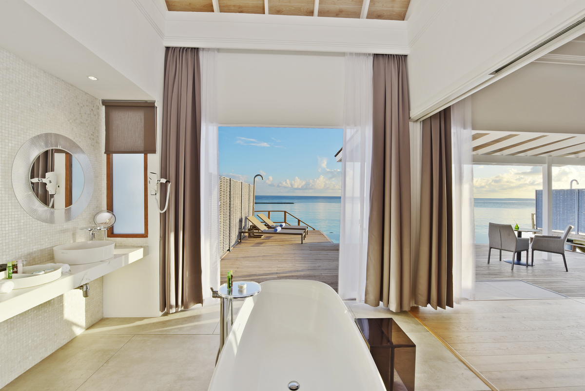 Elegantes Badezimmer mit hellen Bodenfliesen, Mosaikwand und Meerblick.