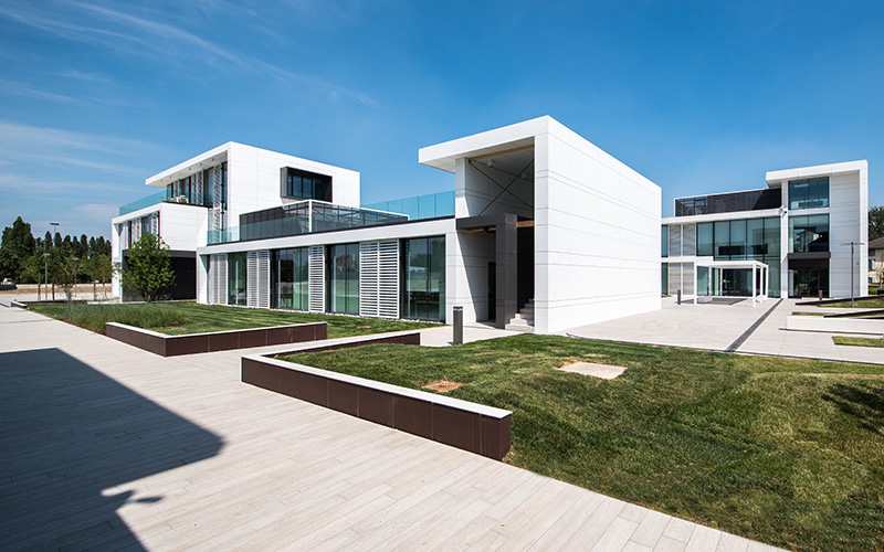 Elegante Außenanlage mit großformatigen hellen Fliesen und modernen Gebäuden.