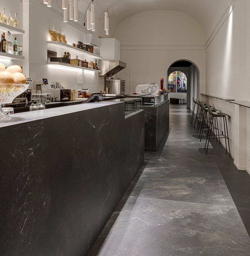 Großformatige, dunkelgraue Fliesen in Steinoptik am Boden und der Theke eines Cafés.