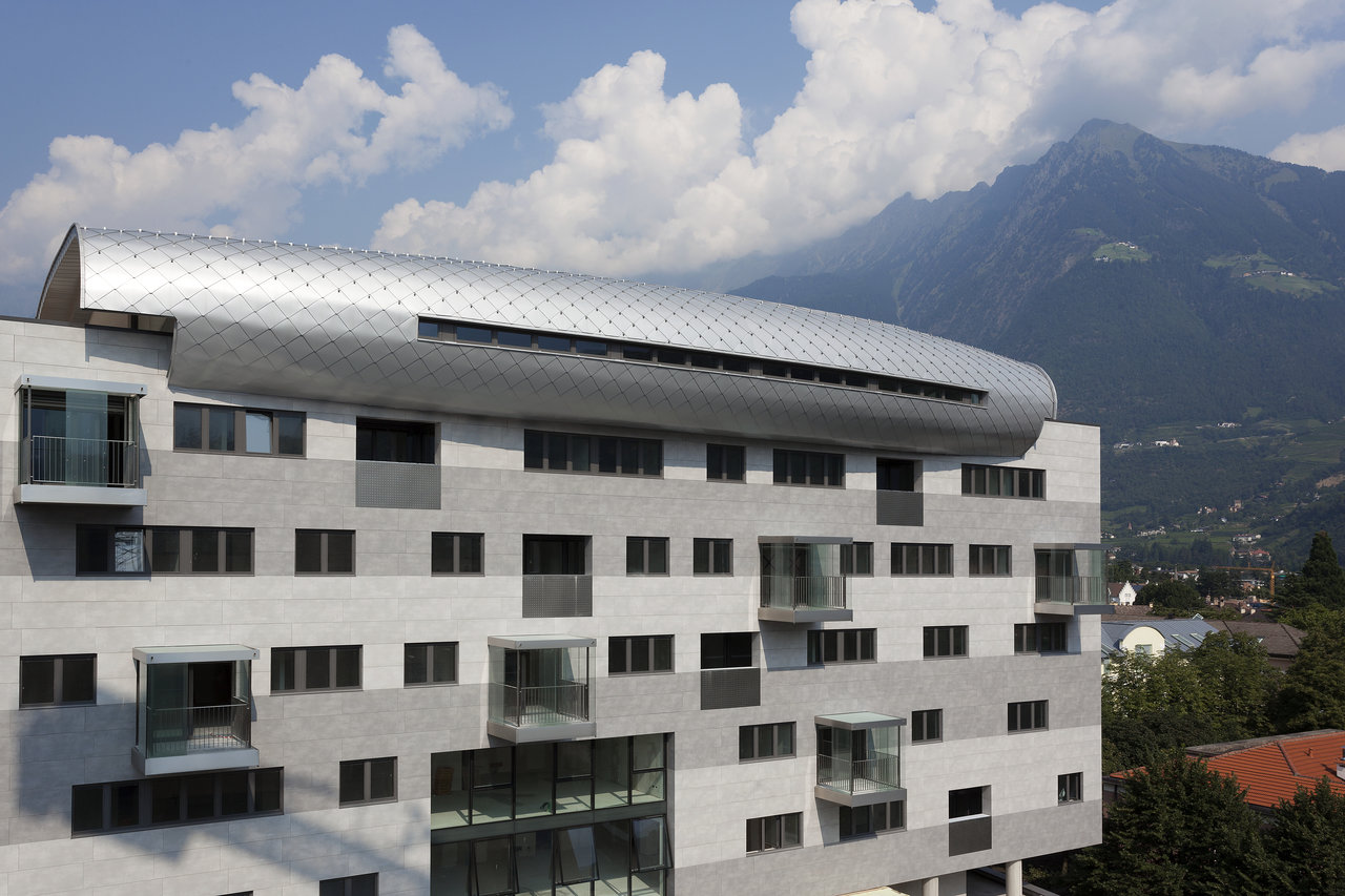 Moderne Architektur: Gebäude mit grauen Fassadenplatten und geschwungenem Metalldach.