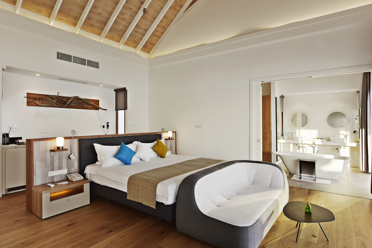 Modernes Schlafzimmer mit Holzbodenoptik und offenem Bad, ideal für stilvolle Fliesenlösungen.