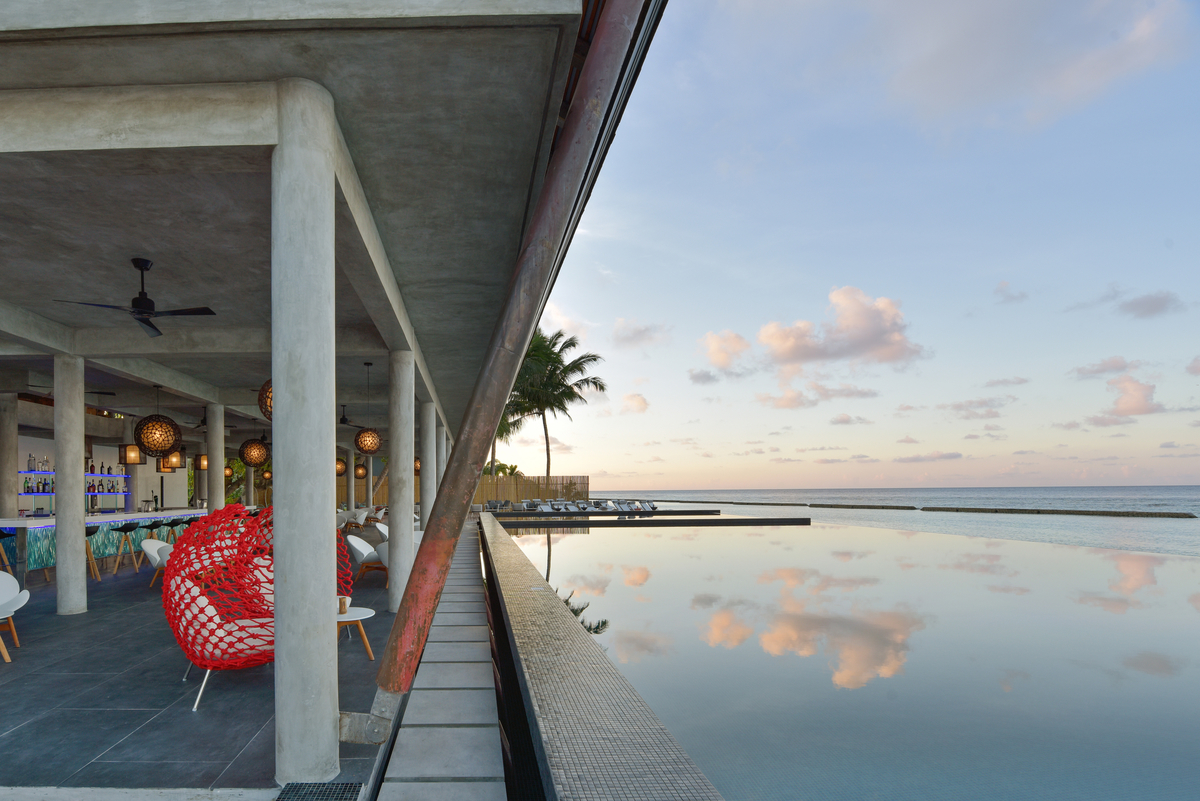 Moderner Outdoor-Bereich mit hochwertigen Fliesen, stilvoller Bar und Infinity-Pool am Meer.