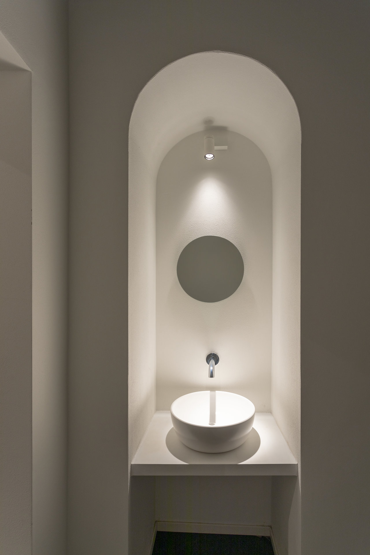 Minimalistisches Bad-Design: Rundes Waschbecken in beleuchteter Nische mit Spiegel.