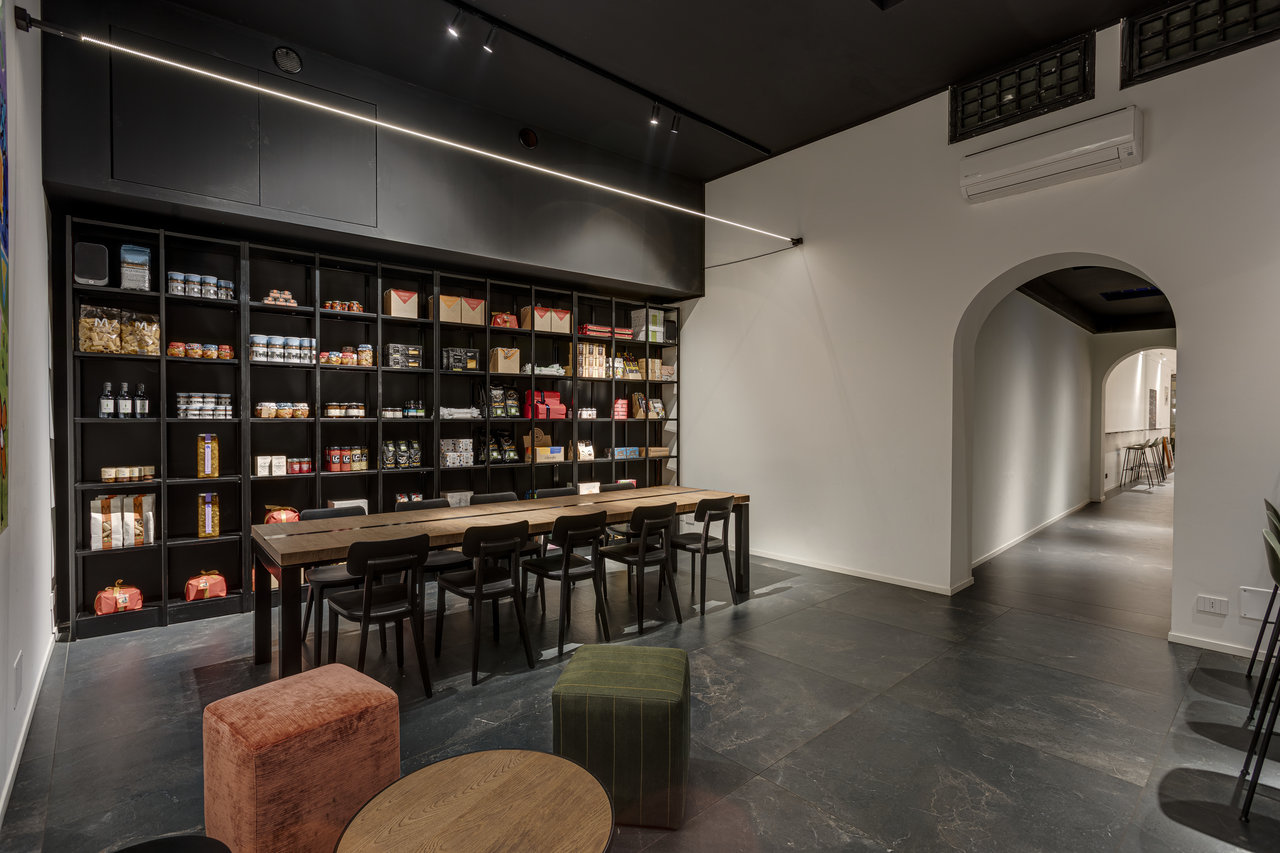 Moderner Showroom mit dunklen Bodenfliesen, langem Tisch und elegantem Wandregal.