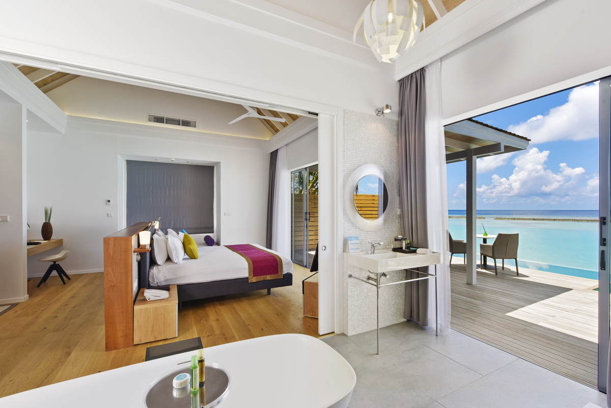 Helle Badfliesen und Holzboden in luxuriöser Suite mit Meerblick-Terrasse.