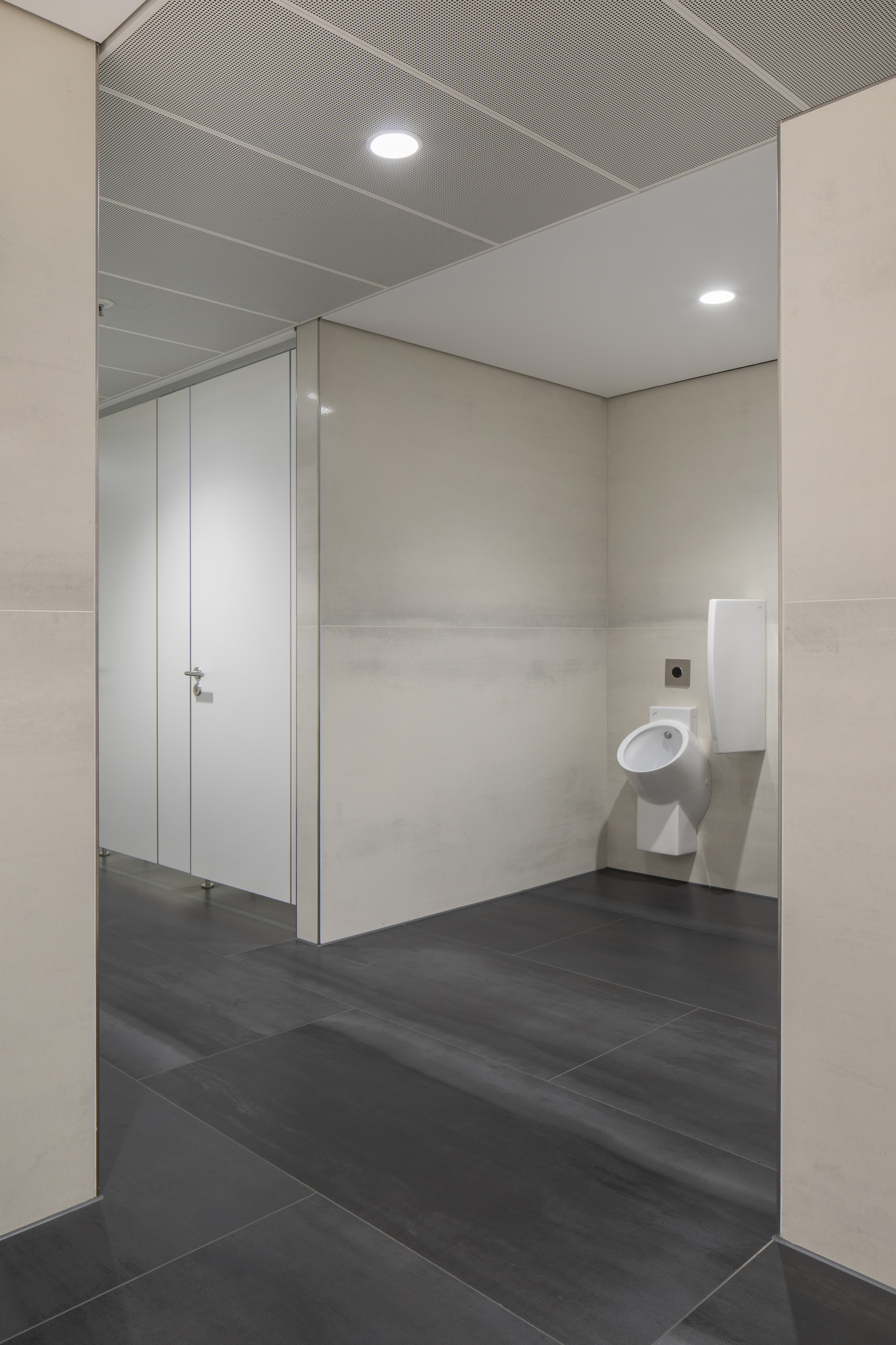 Hochwertige Fliesen in dunklem Grau und hellem Beige in einer modernen Sanitäranlage.